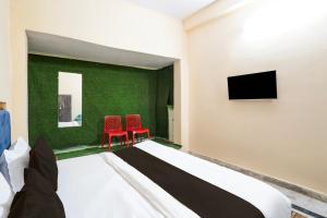 a bedroom with two red chairs and a tv at Hotel O ONMT Inter College Kanpur Formerly Mangalam Palace in Panki