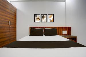 a bedroom with a white bed with three pictures on the wall at Collection O Warje Pune Formerly Choice Guest house in Yerandwane +21 photos
