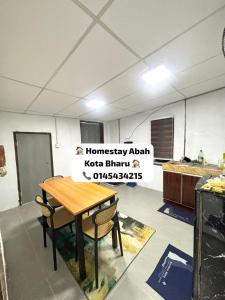 a table and chairs in a room with a sign at Homestay Abah , Kota Bharu, Kelantan in Kota Bharu
