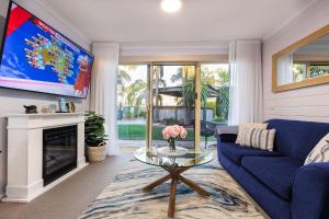 un salon avec un canapé bleu et une télévision dans l'établissement Lakeside Apartments 4, à Merimbula