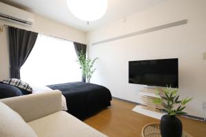 a living room with a couch and a flat screen tv at ウィズ八王子レジデンス 102 in Hachioji