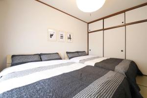 two beds in a bedroom with white cabinets at ウィズ八王子レジデンス 102 in Hachioji
