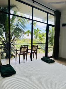 a bedroom with a bed with two chairs and windows at Blue Mountains View in Dambulla