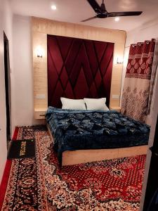 a bedroom with a bed with a red headboard and a rug at Residence Inn Home Stay in Pahalgām