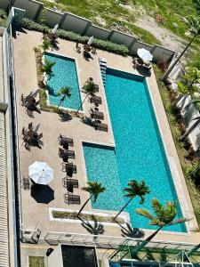 an overhead view of a swimming pool with chairs and umbrellas at Apartamento completo em Ponta de Campina, 2 quartos, piscina, academia e Wi-Fi in Cabedelo