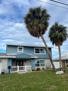 een blauw huis met twee palmbomen in de tuin bij 海湾景观休闲独立屋可垂钓靠近达利博物馆 in St Petersburg