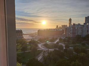 a sunset over a city with the ocean and buildings at Vista y confort - Cerca de todo in Mar del Plata