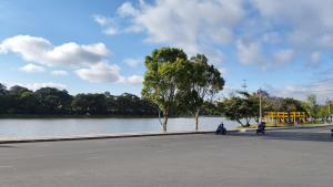 Twee mensen rijden op motoren op een straat naast een rivier. bij Amy Hotel & Apartment in Da Thanh