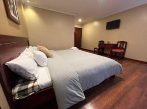 Schlafzimmer mit einem großen weißen Bett und einem Schreibtisch in der Unterkunft Hotel FerAnthon in Cuenca