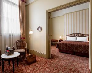 a hotel room with a bed and a chair at Hadley's Orient Hotel in Hobart