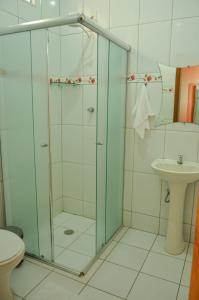une salle de bain avec une douche en verre et un lavabo dans l'établissement Pousada Lirio do Vale, à Cachoeira Paulista