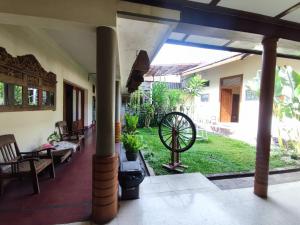 a house with a large porch with a wheel in the yard at Doeloerkoe Homestay in Solo