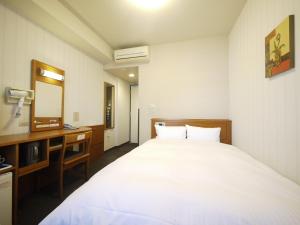 a bedroom with a bed and a desk and a mirror at Hotel Route-Inn Saga Ekimae in Saga