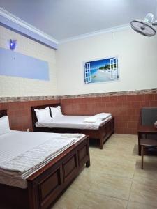 ein Zimmer mit zwei Betten und einem Tisch und einem Fenster in der Unterkunft Minh Hồng Hotel in Ho-Chi-Minh-Stadt