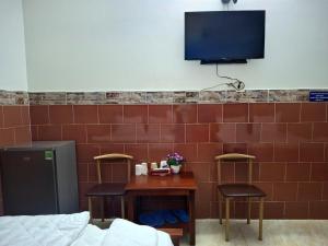 ein Zimmer mit einem Tisch und zwei Stühlen und einem Fernseher an der Wand in der Unterkunft Minh Hồng Hotel in Ho-Chi-Minh-Stadt
