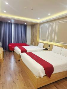 a hotel room with two beds and a red couch at Hotel Villa Ju in Hanoi