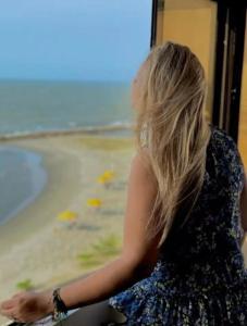 Eine Frau sitzt in einem Zug und blickt auf den Strand hinaus. in der Unterkunft El Dago in Cartagena de Indias
