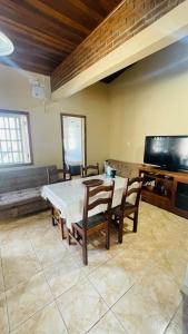 a dining room with a table and chairs and a flat screen tv at Casa com piscina perto da praia in Rio Grande