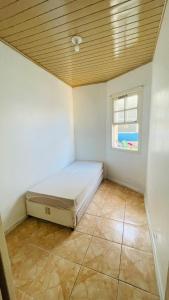 a small bedroom with a bed and a window at Casa com piscina perto da praia in Rio Grande +7 photos
