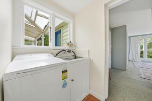 a white kitchen with a sink and a window at Toad Hall - Akaroa Holiday Home in Akaroa +19 photos
