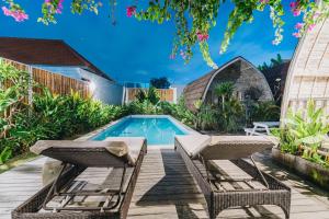 a backyard with a swimming pool and two chairs at Sunshine Village Canggu in Canggu