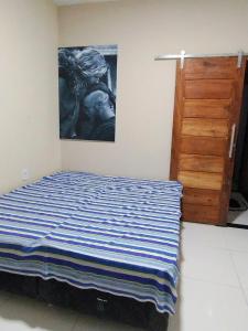 a bedroom with a bed and a painting on the wall at Casa Temporada in Porto Seguro