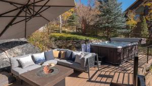 a patio with a couch and an umbrella and a hot tub at Orion Lodge in Steamboat Springs