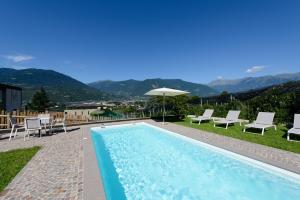 a pool with chairs and an umbrella and mountains at Moar Lodge in Postal