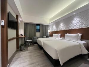 ジョグジャカルタにあるThe Jogja Hotel and Conference Centerのベッド2台とテレビがあるホテルの部屋