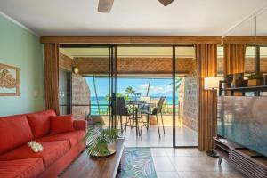 a living room with a red couch and a view of the ocean at Kuleana 321 · KU 321 Spectacular Ocean Views in Kahana