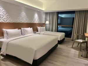 ジョグジャカルタにあるThe Jogja Hotel and Conference Centerのベッド2台とベッドルーム1室が備わるホテルルームです。