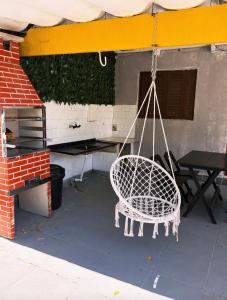 a white chair hanging from a tent with a table at Pousada Lemon Quartos Casal e Família - Ar condicionado e Frigobar - Sesc Bertioga in Bertioga