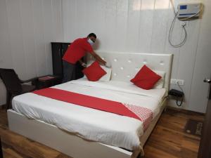a man putting pillows on a bed in a room at OYO 81074 Hotel Adb in Faridabad