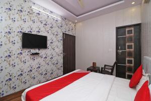 a bedroom with a bed and a tv on a wall at OYO 81074 Hotel Adb in Faridabad +20 photos