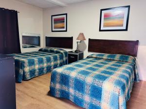 ein Hotelzimmer mit zwei Betten und einem Fernseher in der Unterkunft Budget Motel in Manning