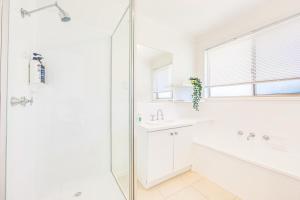 a white bathroom with a shower and a sink at StayAU 4BR Family-Friendly Home near Deakin Uni in Whittington +26 photos