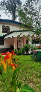 a house with a yard with flowers in front of it at Kalanja Greens Nilagiri Villa in Ooty