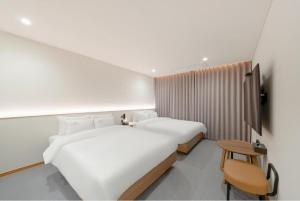een slaapkamer met 2 bedden en een stoel. bij H Avenue Hotel Jeonju Terminal in Jeonju +32 foto's