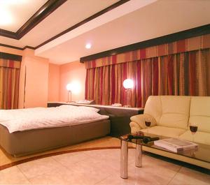 岡山市にあるHotel Queen's Courtのベッドとソファと椅子のある寝室