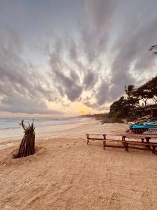 a bench on a beach with a cloudy sky at LIYA BEACH- Luxury Boutique Hotel in Ahangama in Ahangama +18 photos