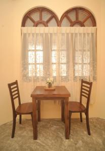 einen Holztisch mit zwei Stühlen und einem Fenster in der Unterkunft Sanmi Runway View Resort in Kimbulapitiya