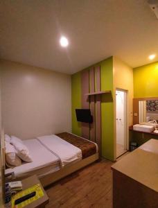 a bedroom with a bed with green and yellow walls at Griya Jogja Hotel in Yogyakarta