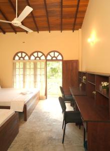 ein Schlafzimmer mit einem Bett und einem Tisch und Stühlen in der Unterkunft Sanmi Runway View Resort in Kimbulapitiya