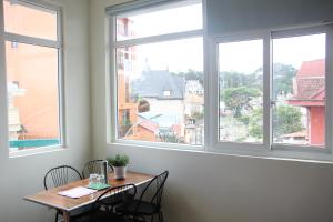 a table and chairs in a room with windows at Thu Van Apartment in Xuan An