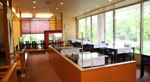 a restaurant with white tables and chairs and windows at Hotel Royal Hill Fukuchiyama and Spa in Fukuchiyama