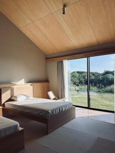 een slaapkamer met twee bedden en een groot raam bij 2R Yakushima in Yakushima