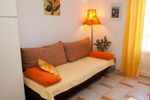 a couch with orange pillows in a living room at Apartments Marija in Vrbnik