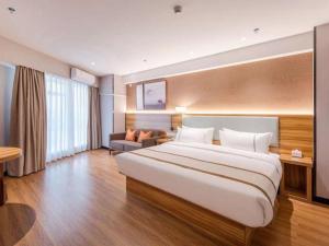 a hotel room with a large bed and a couch at Jtour Inn Wuxi Meiyuan Kaiyuan Temple Metro in Wuxi