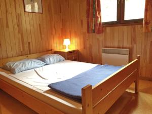 duże łóżko w drewnianym pokoju z lampką w obiekcie La Boverie w mieście Rendeux