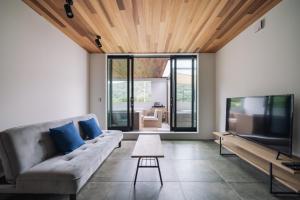 a living room with a couch and a tv at Sanctuary Villa & Sauna Ogimi by Relapool in Banchi